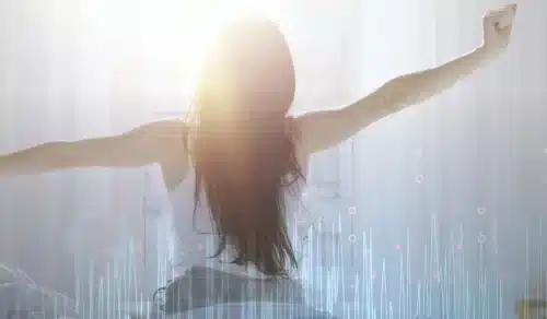Person stretching with arms outstretched toward the light, back to camera, sunlight and abstract data graphics overlaying the scene.