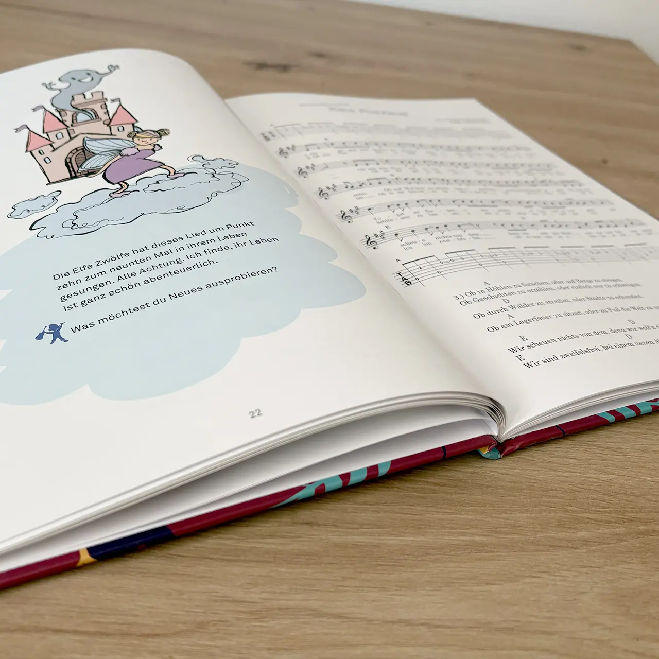 Open children's book showing a fantasy illustration of a pink castle, a girl on a cloud, and a small blue figure, with German text below (page 22).